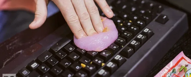 Hands using a microfiber cloth and compressed air to clean your keyboard and mouse on a tidy desk